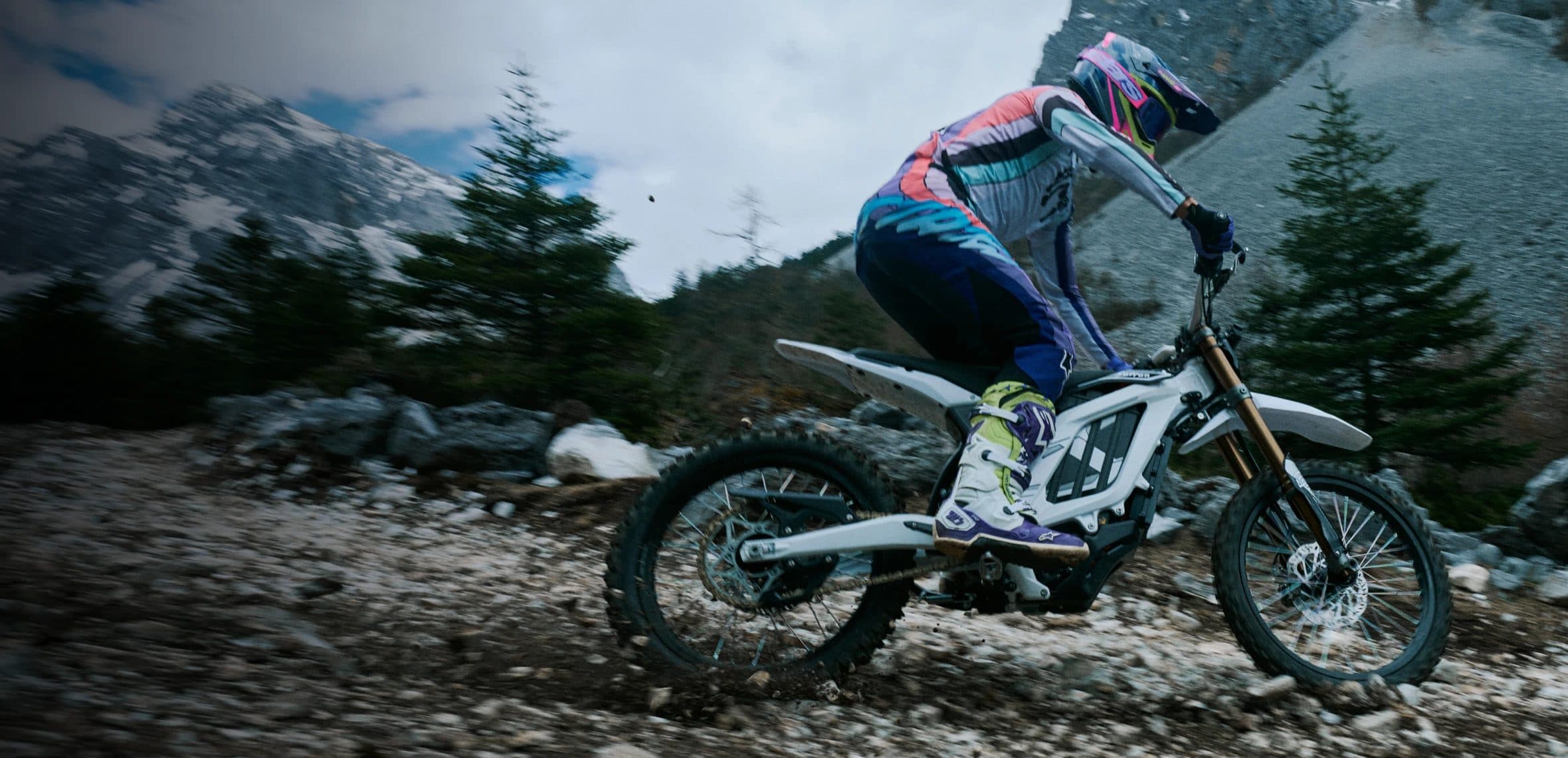 A rider crossing a rocky mountain trail on a Surron