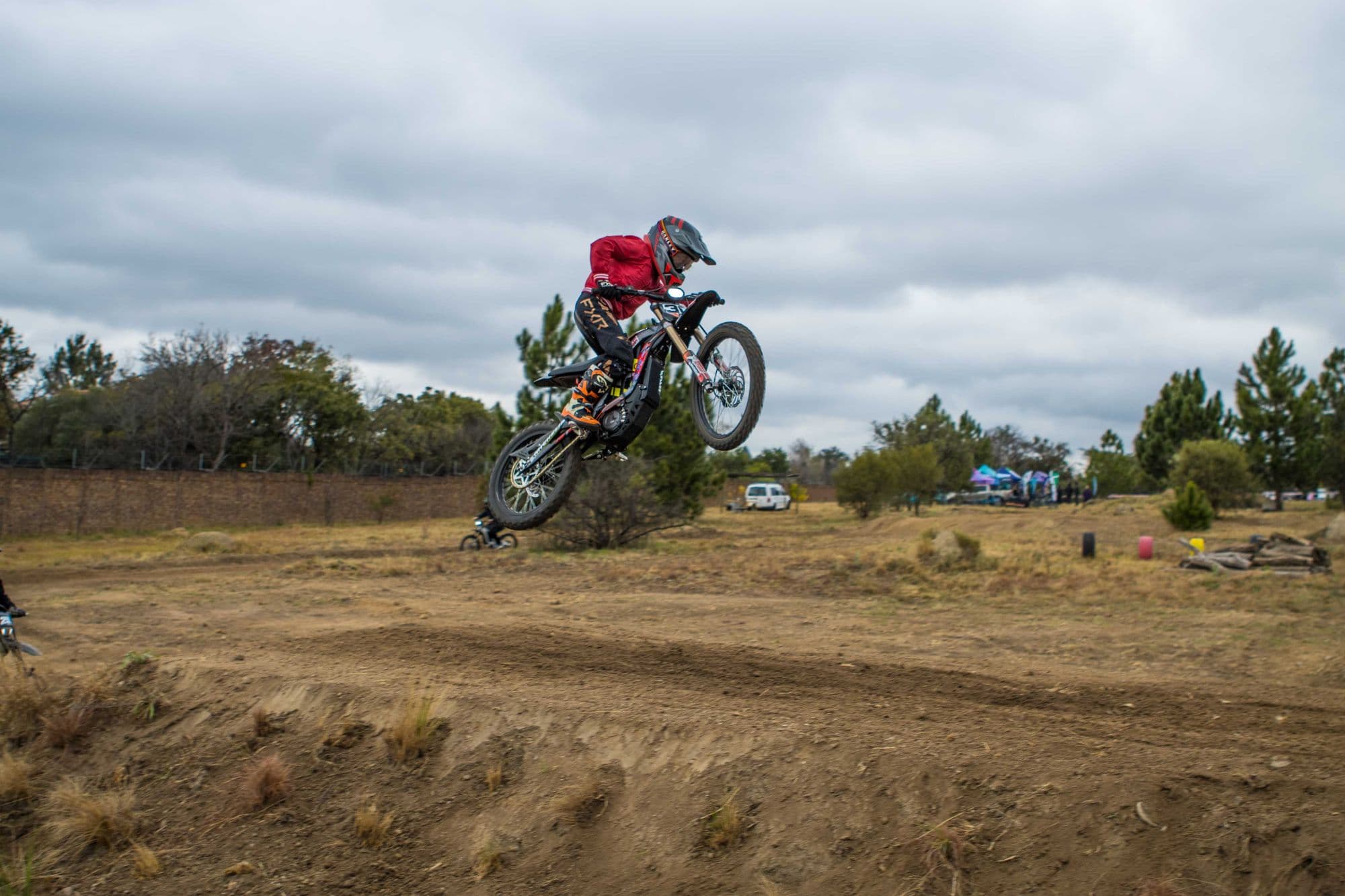 Rider in red jumping a Surron at a track day